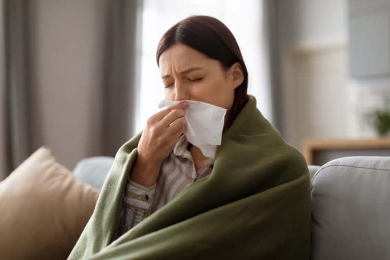 sick-young-woman-wrapped-blanket-blowing-her-nose-768x512
